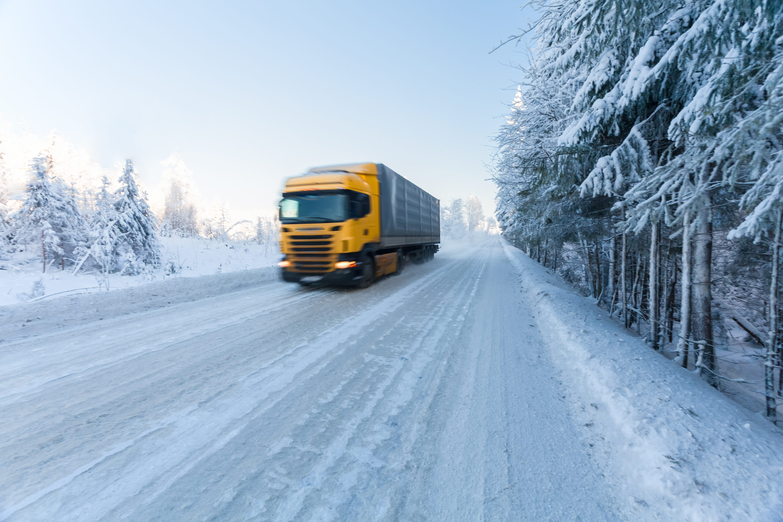 Yellow lorry driving on a snowy road